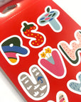 Close up image of sticker of letters designed with fun shapes and colors