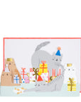 A birthday card with an illustration of a group of cats wearing party hats and celebrating with gifts and pompoms. The card has a red border and a message space at the bottom.