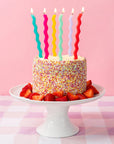 Birthday cake with colorful candles and strawberries on a pink checkered tablecloth