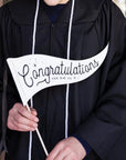 graduate holding "congratulations you did it!" pennant flag