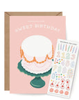Greeting card with a cake illustration and a separate sheet of stickers on a white background