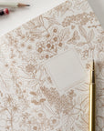 Floral patterned paper with a gold pen on a white surface
