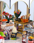 Miniature model of a greenhouse with various flowers, plants, and furniture