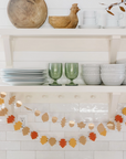 Two autumn leaf garland hung underneath kitchen open shelves