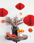 Decorative table setting with red lanterns, fruits, and a vase on a white background