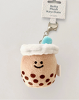 A plush keychain designed to look like a boba tea drink with a smiling face, brown sugar dots, and a blue straw on top.