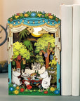 Moomin themed theater miniature set with moomin characters having a feast, displayed next to books