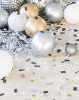 Confetti and balloon filled floor with some silver metallic tinsel and portions of disco balloon and ball