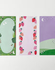 Three sheets of notepad. left sheet of garden with trees, middle sheet with strawverries and right sheet of sheeps in a field