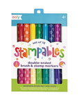 A set of 18 double-ended stamp and brush markers in various colors, packaged in a clear plastic tube with a blue and green label that features the brand ooly and the product name Stampables.