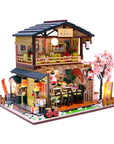 Model of a Japanese-style building with cherry blossom tree on a white background