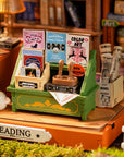 detailed picture of a miniature bookshop with books and stationery items, and sleepy kitten