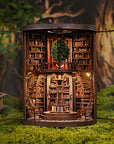 Miniature model of a library with bookshelves and a staircase, set against a natural background.