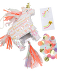 An opened up pink unicorn-shaped piñata with neon tassels and gold foil details, containing confetti and temporary tattoos inside.
