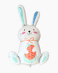 A colorful balloon shaped like a bunny with a basket and flowers, predominantly white and blue with orange accents.