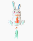 A colorful balloon shaped like a bunny with a basket and flowers, predominantly white and blue with orange accents.