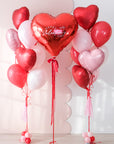 Heart-shaped balloon bouquets with a 'Happy Valentine's Day' red heart balloon on a light background