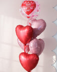 Heart-shaped balloons with 'Happy Valentine's Day!' clear ballloon, on a light pink background