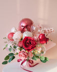 Bouquet of flowers with red, clear, and pink balloons on a light pink background