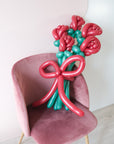 5 twisted balloon roses on a pink chair