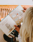 Child reading a children's book with cartoon animals