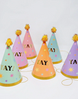 A set of 6 party hats in pastel rainbow colors wiht gold YAY! text and gold pom topper