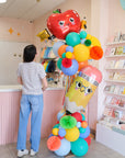 person standing next to deluxe balloon tower with back to school shapes
