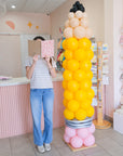 a person reading a notebook next to pencil balloon column for scale