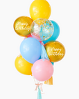 A balloon bouquet with a mix of solid colored balloons in blue, yellow, pink, and green, along with two metallic orb balloons, one with 'Happy Birthday' text, and a clear confetti balloon. There is a tassel and a ribbon bow on the arrangement.
