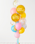 A balloon bouquet with a mix of solid colored balloons in blue, yellow, pink, and green, along with two metallic orb balloon with 'Happy Birthday' text, and a clear confetti balloon. There is a tassel and a ribbon bow on the arrangement.