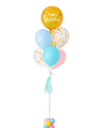 A balloon bouquet with a mix of solid colored balloons in blue, yellow, pink, and green, along with one metallic orb balloon with 'Happy Birthday' text, and a clear confetti balloon. There is a tassel and a ribbon bow on the arrangement.