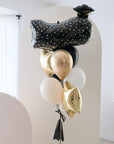 A balloon bouquet with black, gold, and silver balloons.
