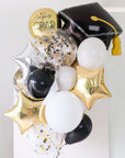 Graduation-themed balloons with a black cap, gold confetti, and foil stars on a light background