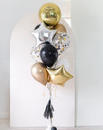 gold, black, white, cream, and silver graduation balloons in front of an arch backdrop