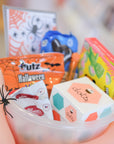 Assorted Halloween-themed candy and toys in a bowl with a blurred background