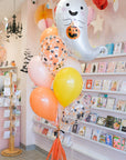 Halloween-themed balloon bouquet with a ghost design in a store setting.