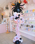 Balloon sculpture of a spider in a store setting with shelves and decor.
