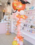 Halloween-themed balloon arrangement in a store with card displays.