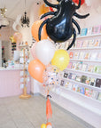 Spider-shaped balloon with colorful balloons in a store setting