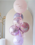 A bunch of balloons with 'Happy Mother's Day' written on one, in colors pink, purple, and clear, with some balloons having confetti inside.
