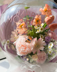 Close up of bouquet of faux spring flowers in a transparent balloon featuring a small butterfly