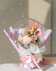 Bouquet of faux spring flowers in a transparent balloon with 'Happy Mother's Day' text, wrapped in lavender paper and ribbon