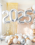 silver 2025 number balloons with cream, gold and silver balloons on the floor