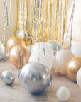 Cream, white, gold and silver balloons on the floor with a gold tinsel curtain and cream backdrop