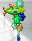 A bunch of colorful balloons including a large green one with 'You-O-Fish-ally The Best Dad' printed on it, along with various other balloons in shades of blue and red.
