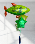 A bunch of colorful balloons including a large green one with 'You-O-Fish-ally The Best Dad' printed on it, along with various other balloons in shades of blue and red.