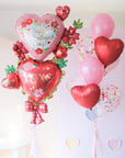 Anotehr view of the balloon set with a double stack of floral heart balloons in various shades of red and pink, with bows and mini hearts, designed for Valentine's Day.