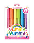 A pack of ooly brand scented highlighters, featuring a set of 6 pastel highlighters in a box with colorful fruit illustrations and a 'Yummy' theme.