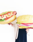 girl holding hotdog and burger balloons