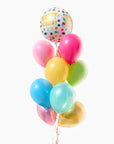A bouquet of colorful balloons including shades of pink, blue, green, yellow, and gold, with a round happy birthday balloon on top.